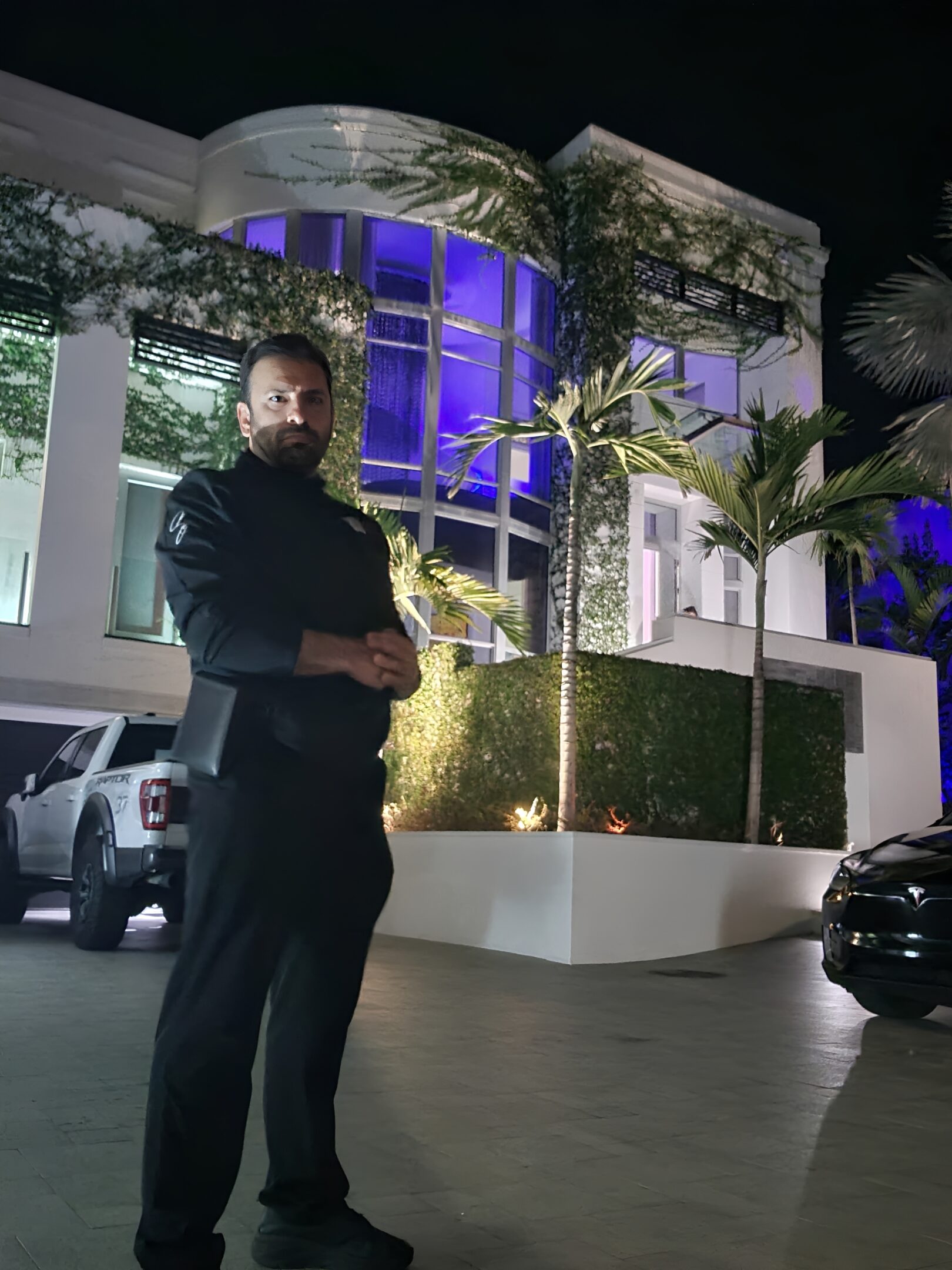 Man standing outside illuminated modern building at night.