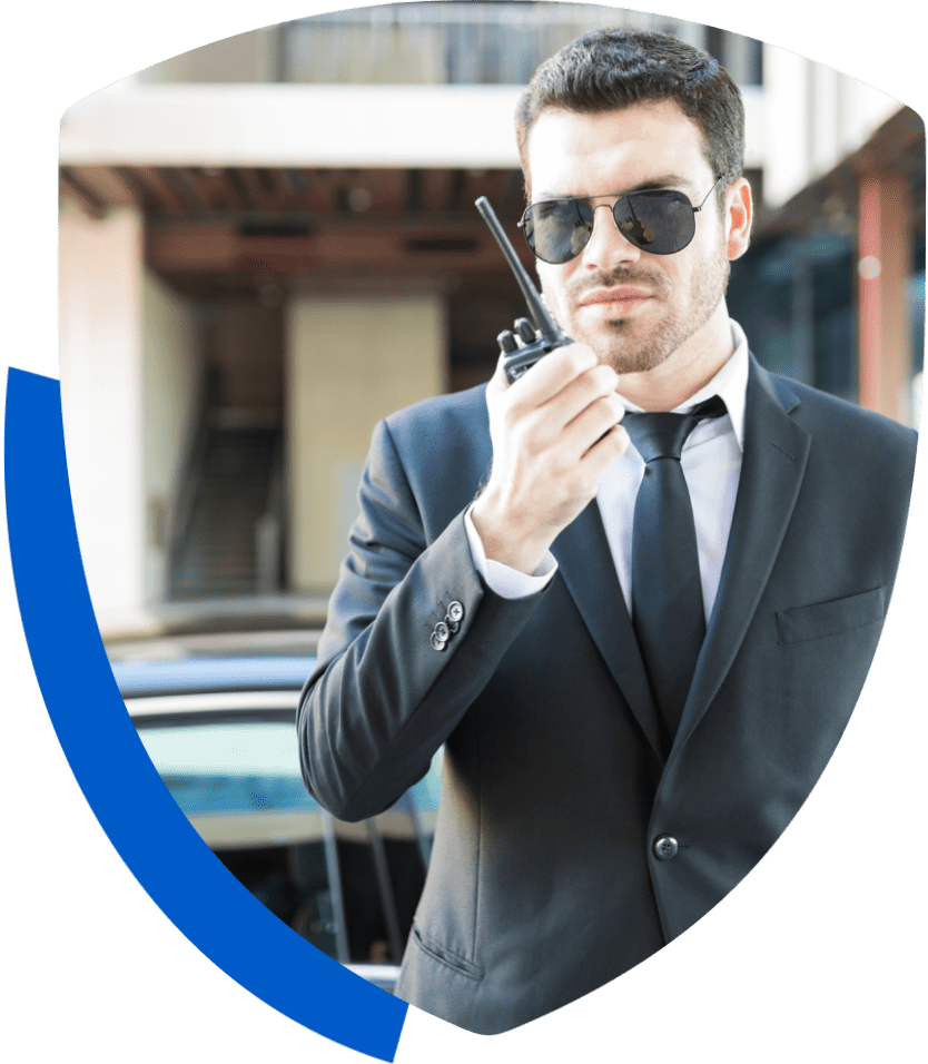 Man in suit with sunglasses, holding walkie-talkie.